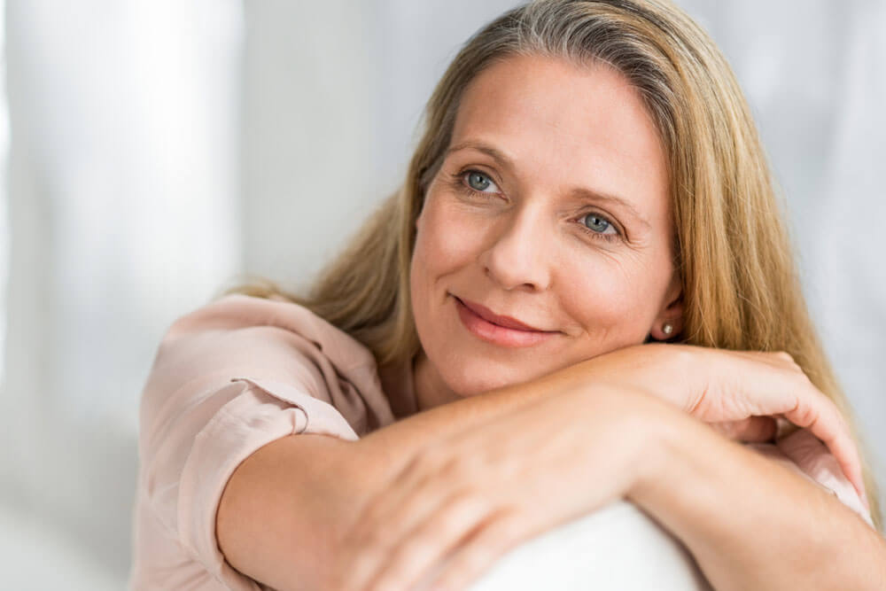 Smiling senior woman sitting on couch and thinking about her new idea